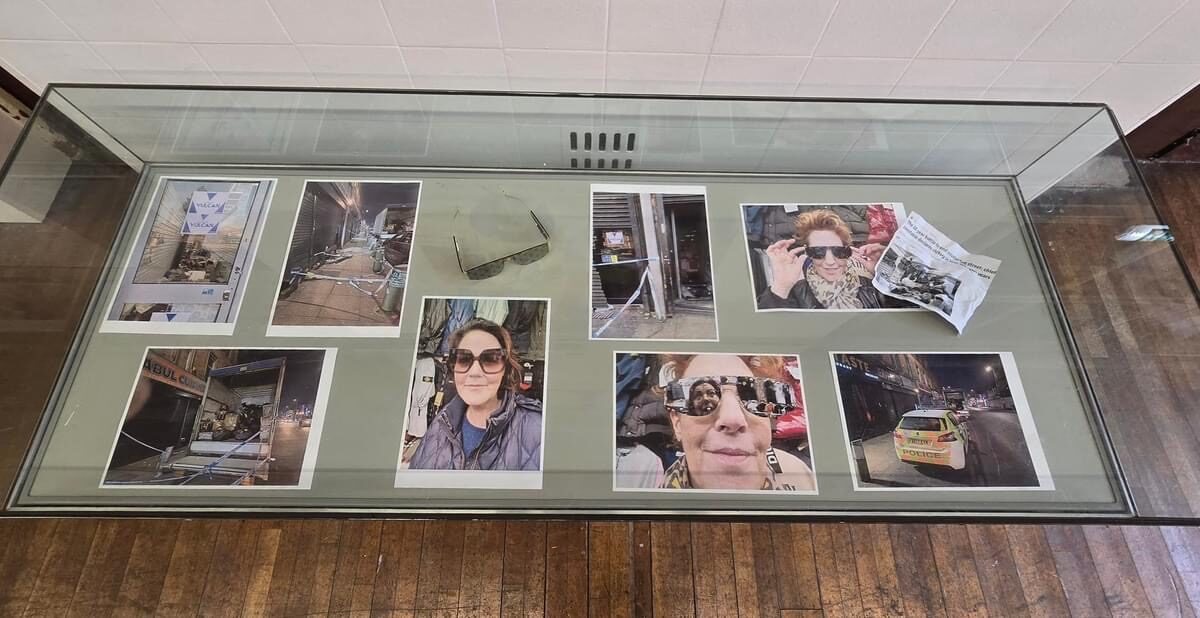 A glass display case documenting the piece, with photographs of the raided shops, the counterfeit sunglasses and the police response