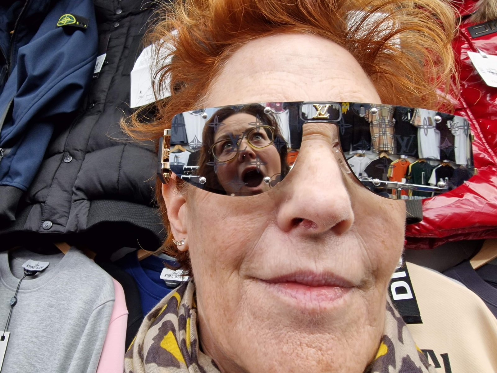 Louise Garman trying on sunglasses in a shop selling counterfeit goods, reflected in the lens