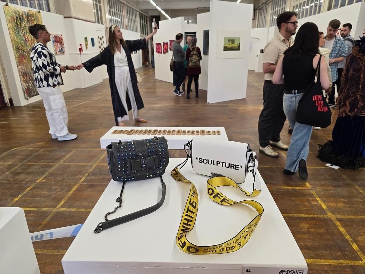 A private view with a plinth displaying counterfeit designer handbags labelled &lsquo;Sculpture&rsquo;, part of the Strangeways installation, at the neo:artists Open exhibition, Rogue Gallery, Manchester