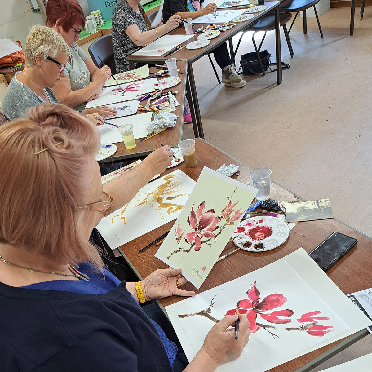 Workshop participants painting pink magnolia blossoms in the Chinese painting style